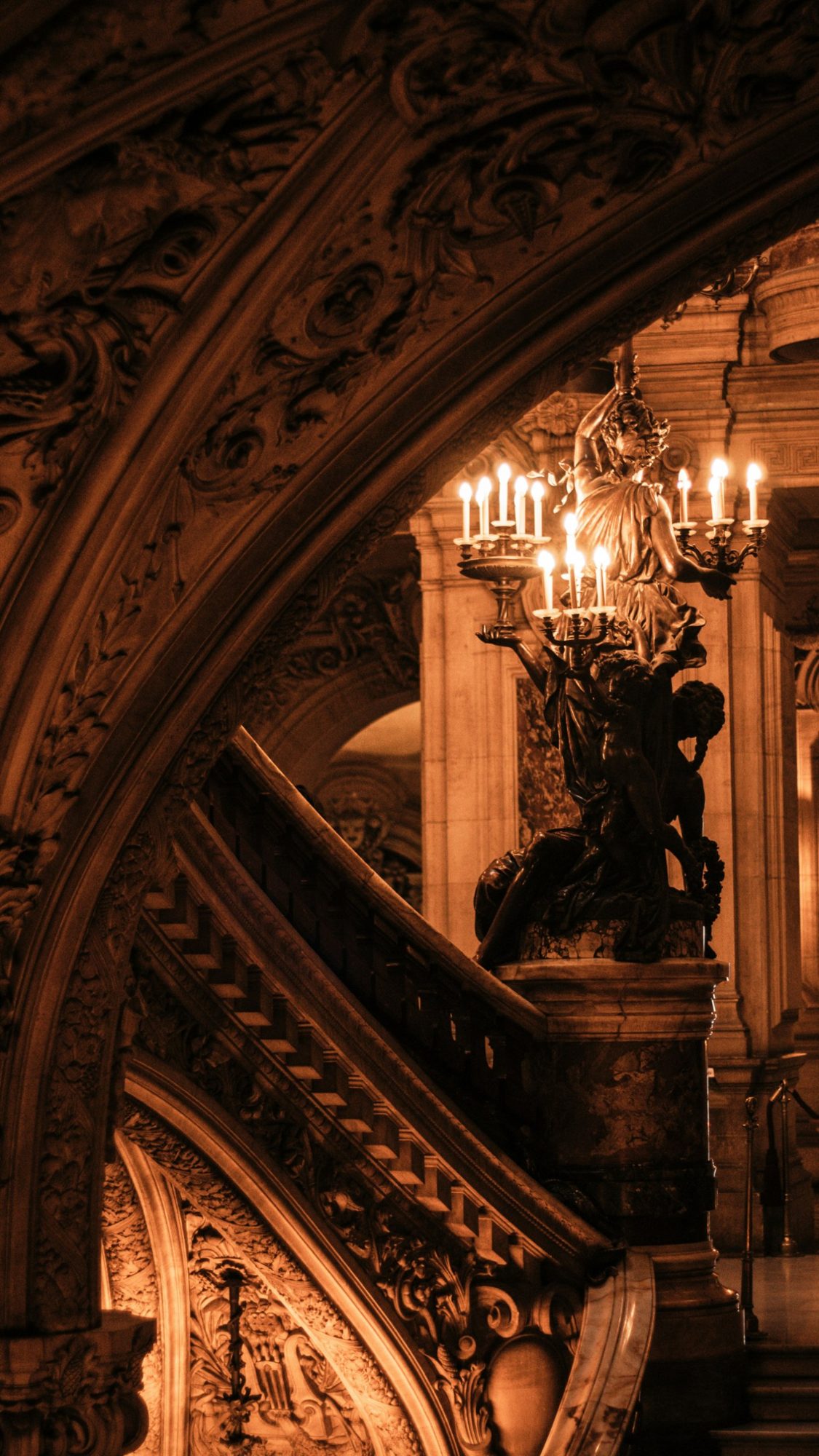 Candlelit bronze statue on the grand staircase of the Paris Opera