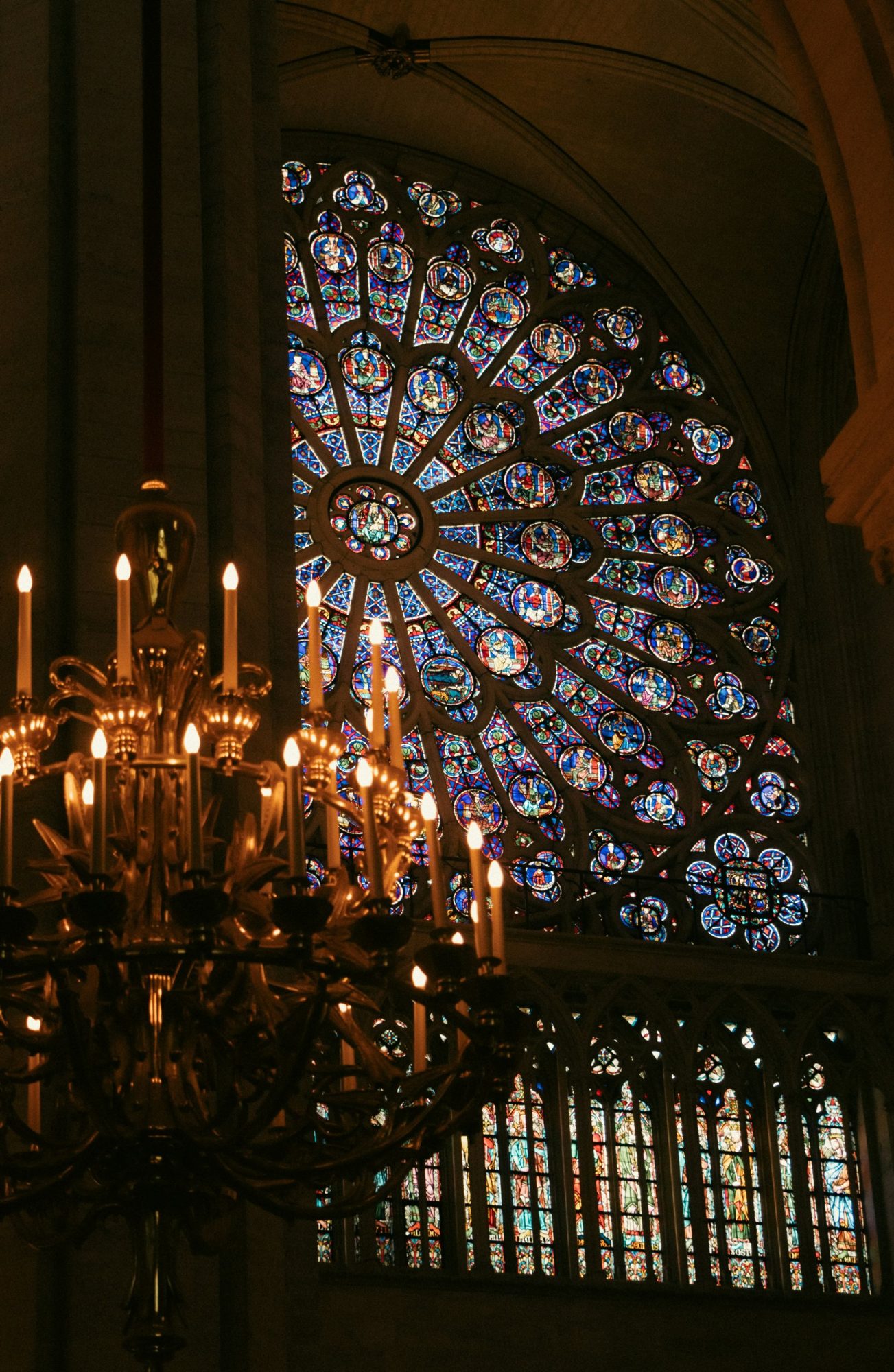 Candlelit chandelier before a glowing rose window